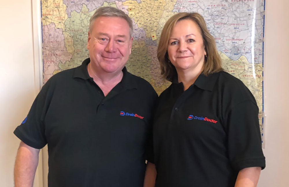 Two Drain Doctor franchisees smiling, looking at the camera in an office
