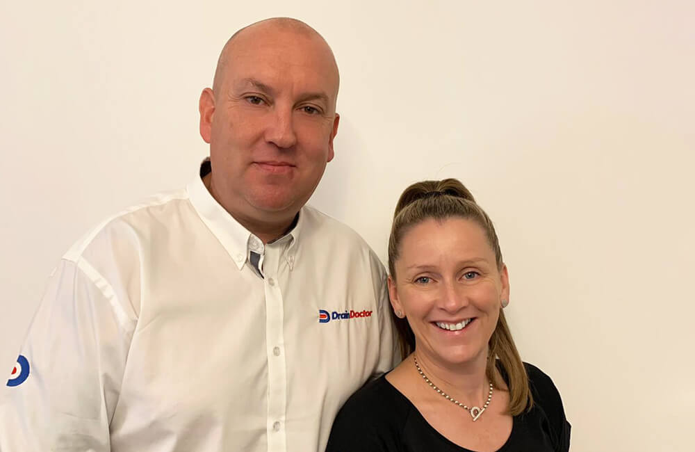 Two Drain Doctor franchisees smiling, looking at the camera in an office